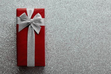 Mutlu noeller. Parlak gümüş parıltılı arka planda fotokopi alanı olan Noel hediyesi kutusunun en üst görüntüsü. Noel konsepti geçmişi