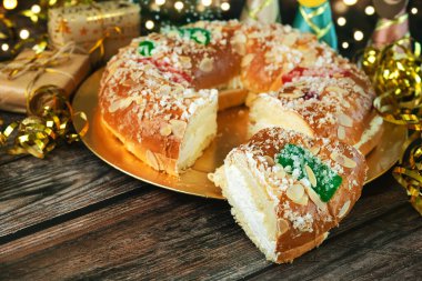 Kremalı Roscon de Reyes ve masada noel süsleri. Krallar Günü konsepti ispanyolca üç papaz pastası. Noel için tipik İspanyol tatlısı. Seçici odak