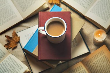 Kitap manzarası ve sonbahar yapraklı bir fincan kahve. Seçici odak