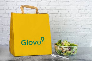 Masadaki salatanın yanında Glovo Gıda Kağıdı Paketi.