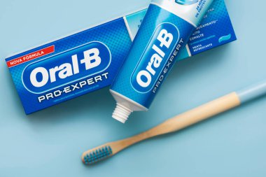 Mavi arka planda Oral B diş macunu ve bambu diş fırçası bulunan bir kutu Oral B diş macunu.