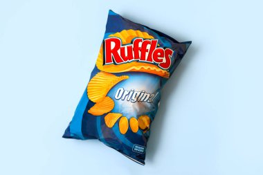Mavi arka planda bir paket patates cipsi. Patates cipsi atıyor.