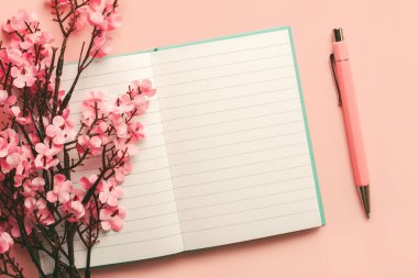 Fotokopi alanı açık boş günlüğün üst görünümü, pembe arkaplan üzerinde pembe kalem ve badem çiçekleri