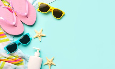 Yaz tatili konsepti. Plaj havlusu, parmak arası terlik, güneş gözlüğü, güneş kremi ve mavi arkaplan üzerinde yazı için yeri olan denizyıldızı manzarası.