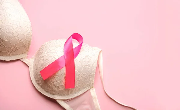 Breast cancer concept. Women's bra and pink ribbon symbol breast cancer awareness with space for text over pink background