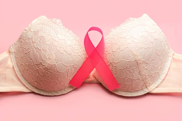 Breast cancer concept. Top view of Women\'s bra and pink ribbon symbol breast cancer awareness over pink background