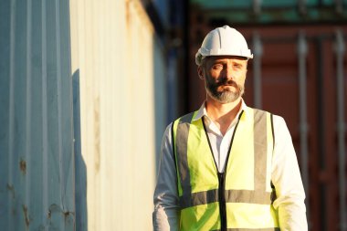 Foreman kontrol kargo nakliye gemisinden ithalat için konteynır kutusu yüklüyor. Deniz limanında nakliye konteynırları.