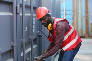 Foreman kontrol kargo nakliye gemisinden ithalat için konteynır kutusu yüklüyor. Deniz limanında nakliye konteynırları.