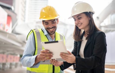 Mühendisler ve yöneticiler inşaat alanında planları tartışıyorlar..