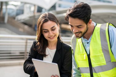 Mühendisler ve yöneticiler inşaat alanında planları tartışıyorlar..