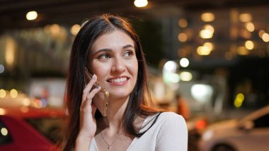 Genç kadın konuşurken birileriyle onun cep telefonu süre seyir içine mesafe mutlu yüz ifadesi ile kapatmak.