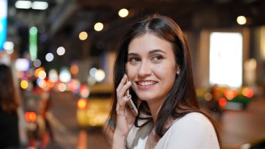 Genç kadın konuşurken birileriyle onun cep telefonu süre seyir içine mesafe mutlu yüz ifadesi ile kapatmak.