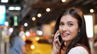 Genç kadın konuşurken birileriyle onun cep telefonu süre seyir içine mesafe mutlu yüz ifadesi ile kapatmak.