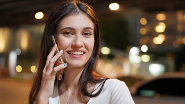 Genç kadın konuşurken birileriyle onun cep telefonu süre seyir içine mesafe mutlu yüz ifadesi ile kapatmak.
