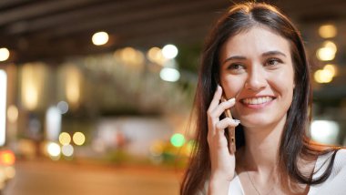 Genç kadın konuşurken birileriyle onun cep telefonu süre seyir içine mesafe mutlu yüz ifadesi ile kapatmak.