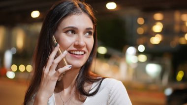 Genç kadın konuşurken birileriyle onun cep telefonu süre seyir içine mesafe mutlu yüz ifadesi ile kapatmak.