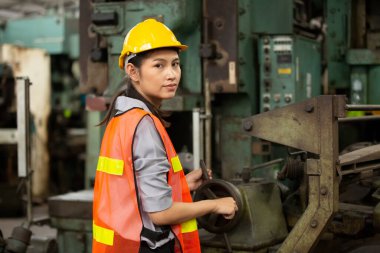 İşaretli gömlekli genç teknisyenin profil görüntüsü endüstriyel makineyi denetliyor