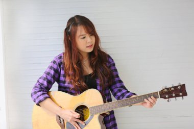 Kız mikrofonda şarkı söylüyor ve gitar çalıyor.