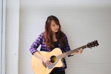 Kız mikrofonda şarkı söylüyor ve gitar çalıyor.