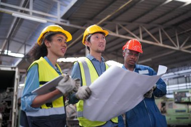 Profesyonel Ağır Sanayi Mühendisi / İşçi Güvenlik Üniforması, Gözlük ve Sert Şapka Giyen Portresi. Arka planda Odaklanmamış Büyük Endüstriyel Fabrika