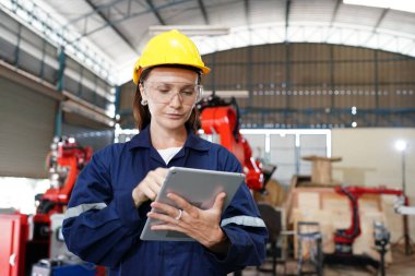 Endüstriyel teçhizat ve robot kollarını büyük elektrik elektronik telleri ve kablo imalat fabrikasında yerleştirerek, kontrol ederek ve test ederek çalışan profesyonel endüstriyel kadın fabrika çalışanı.