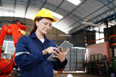 Endüstriyel teçhizat ve robot kollarını büyük elektrik elektronik telleri ve kablo imalat fabrikasında yerleştirerek, kontrol ederek ve test ederek çalışan profesyonel endüstriyel kadın fabrika çalışanı.