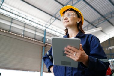 Endüstriyel teçhizat ve robot kollarını büyük elektrik elektronik telleri ve kablo imalat fabrikasında yerleştirerek, kontrol ederek ve test ederek çalışan profesyonel endüstriyel kadın fabrika çalışanı.