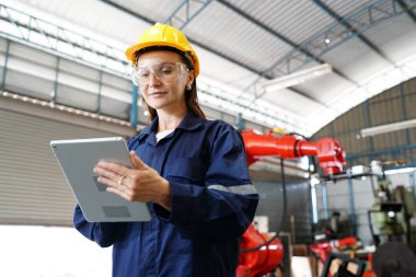 Endüstriyel teçhizat ve robot kollarını büyük elektrik elektronik telleri ve kablo imalat fabrikasında yerleştirerek, kontrol ederek ve test ederek çalışan profesyonel endüstriyel kadın fabrika çalışanı.