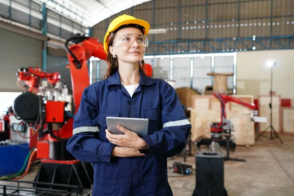 Professional young industrial factory woman employee working with machine parts putting, checking and testing industrial equipments and robot arms in large Electric electronics wire and cable manufacturing plant factory