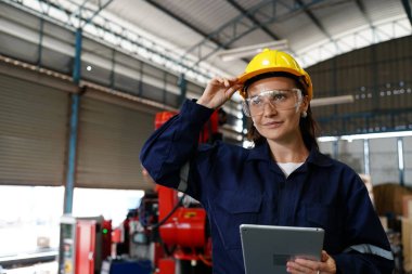 Endüstriyel teçhizat ve robot kollarını büyük elektrik elektronik telleri ve kablo imalat fabrikasında yerleştirerek, kontrol ederek ve test ederek çalışan profesyonel endüstriyel kadın fabrika çalışanı.