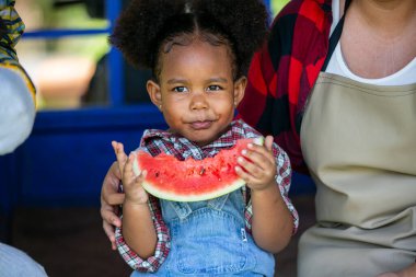 Küçük afro kız organik çiftlikteki fidanlıkta karpuz yemekten hoşlanıyor..