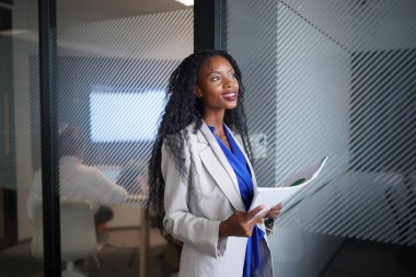 İspanyol asıllı ve özgüvenli afro iş kadını, yeni açılan modern ofiste çalışıyor..