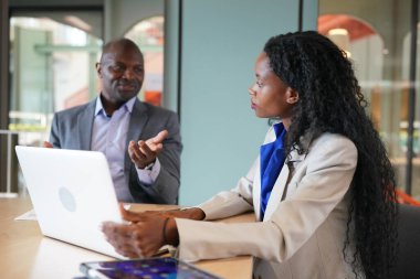 Genç iş adamları ve meslektaşlarının toplantıda laptopta ve dokunmatik kağıtları tartışırken görüntüsü