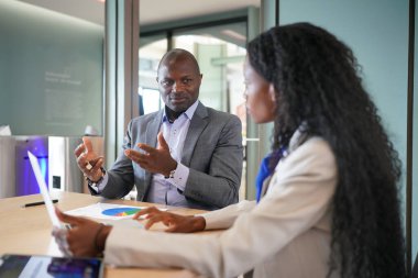 Genç iş adamları ve meslektaşlarının toplantıda laptopta ve dokunmatik kağıtları tartışırken görüntüsü