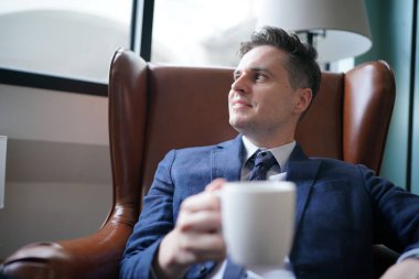 Modern ofis binasındaki başarılı iş adamının portresi. İş adamı kameraya bakıyor ve gülümsüyor. Yakışıklı bir adamın portresi.