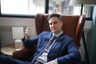 Modern ofis binasındaki başarılı iş adamının portresi. İş adamı kameraya bakıyor ve gülümsüyor. Yakışıklı bir adamın portresi.