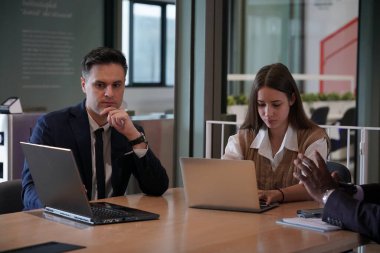 Genç iş adamları ve meslektaşlarının toplantıda laptopta ve dokunmatik kağıtları tartışırken görüntüsü