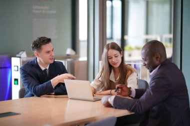 Genç iş adamları ve meslektaşlarının toplantıda laptopta ve dokunmatik kağıtları tartışırken görüntüsü