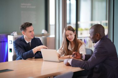 Genç iş adamları ve meslektaşlarının toplantıda laptopta ve dokunmatik kağıtları tartışırken görüntüsü