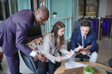Genç iş adamları ve meslektaşlarının toplantıda laptopta ve dokunmatik kağıtları tartışırken görüntüsü
