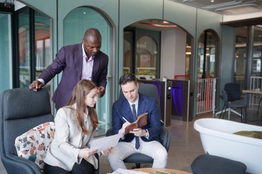 Genç iş adamları ve meslektaşlarının toplantıda laptopta ve dokunmatik kağıtları tartışırken görüntüsü