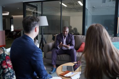 Genç iş adamları ve meslektaşlarının toplantıda laptopta ve dokunmatik kağıtları tartışırken görüntüsü