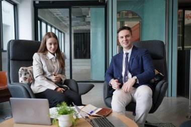 Genç iş adamları ve meslektaşlarının toplantıda laptopta ve dokunmatik kağıtları tartışırken görüntüsü