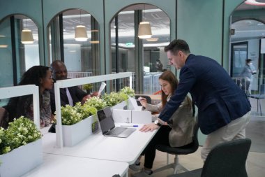 Genç iş adamları ve meslektaşlarının toplantıda laptopta ve dokunmatik kağıtları tartışırken görüntüsü