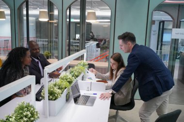 Genç iş adamları ve meslektaşlarının toplantıda laptopta ve dokunmatik kağıtları tartışırken görüntüsü