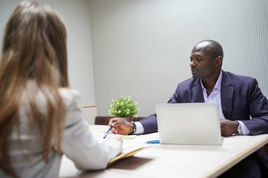 Genç iş adamları ve meslektaşlarının toplantıda laptopta ve dokunmatik kağıtları tartışırken görüntüsü