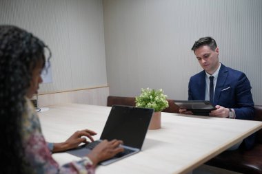 Genç iş adamları ve meslektaşlarının toplantıda laptopta ve dokunmatik kağıtları tartışırken görüntüsü