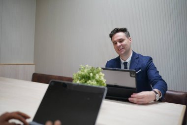 Genç iş adamları ve meslektaşlarının toplantıda laptopta ve dokunmatik kağıtları tartışırken görüntüsü