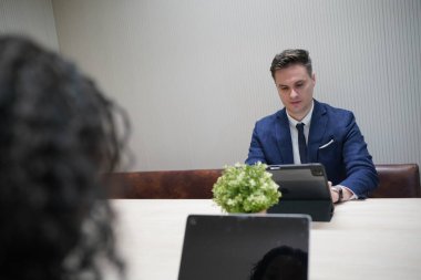 Genç iş adamları ve meslektaşlarının toplantıda laptopta ve dokunmatik kağıtları tartışırken görüntüsü