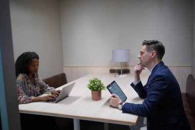 Genç iş adamları ve meslektaşlarının toplantıda laptopta ve dokunmatik kağıtları tartışırken görüntüsü